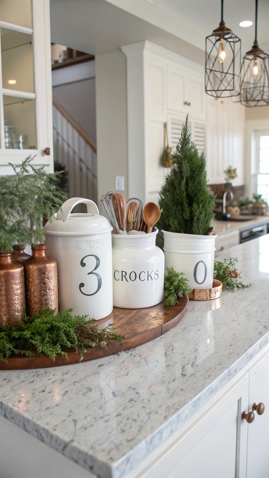 Modern farmhouse kitchen island featuring hand-numbered white ceramic crocks with utensil sets, green plants, and copper accents on a marble countertop